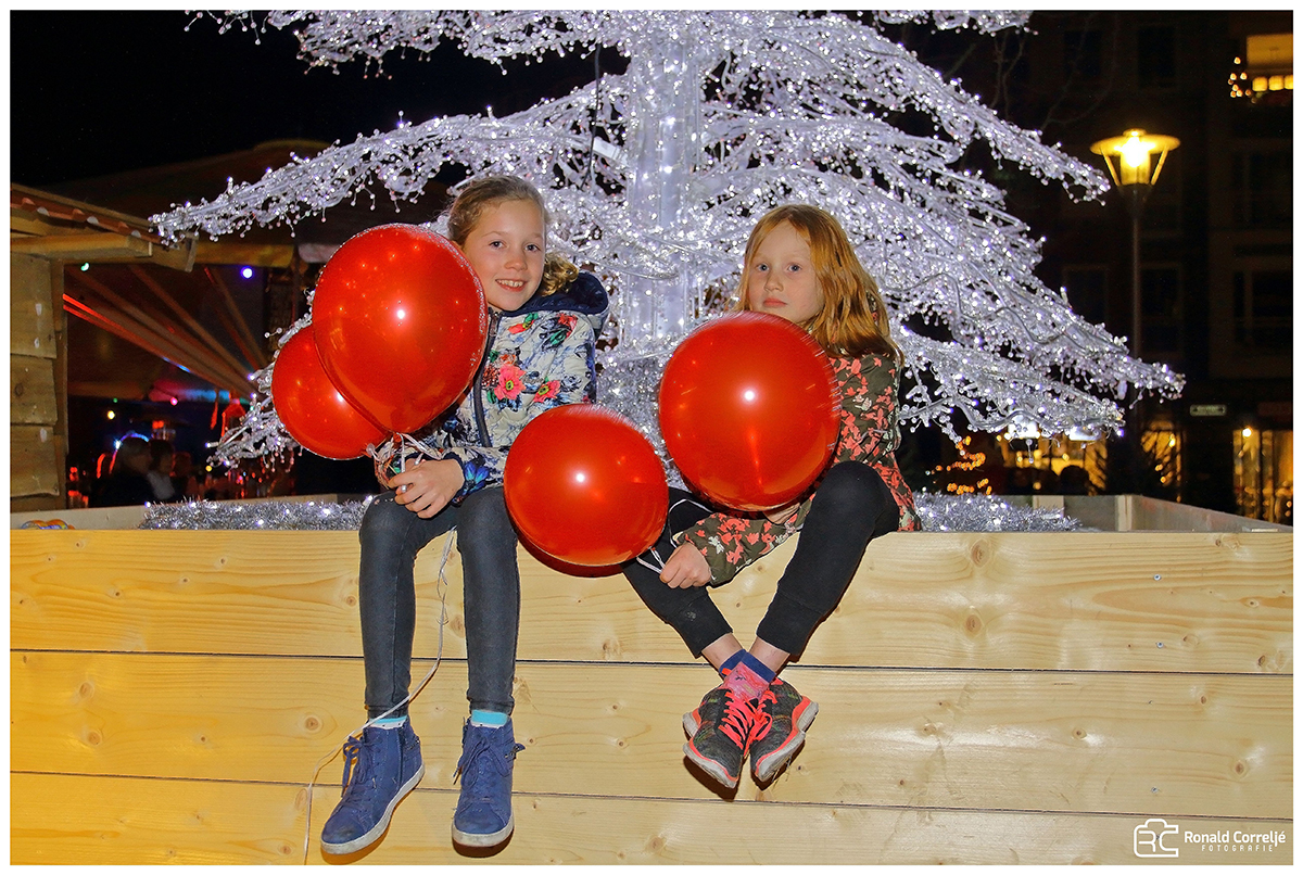 twee meisjes zittend op een bank met ballonnen